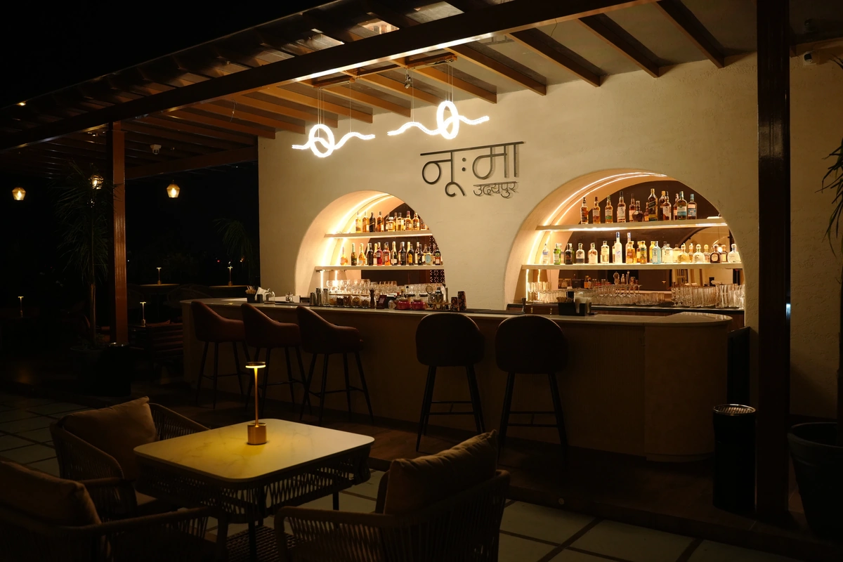 The NOUMA bar at night with glowing arched shelves of bottles